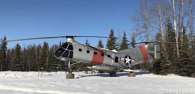 Two-bladed old helicopter mounted on concrete pads in the snow.