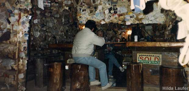 People sit at the bar inside the Bird House; the walls are covered with tacked on photos and underwear.