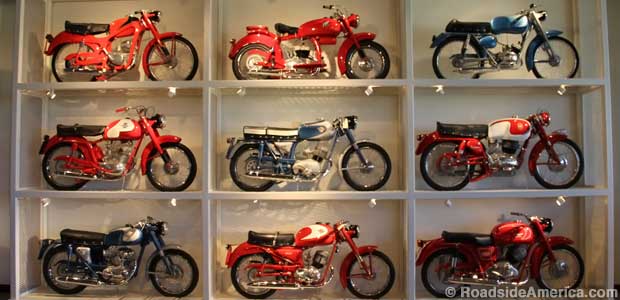 Wall rack displays nine colorful motorcycles.