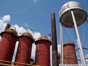 Rust-red tanks and silver water tower of giant outdoor former ironworks furnaces.