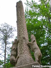 Monument of two dogs looking upward, grasping a tree trunk, at the entrance to the Coon Dog Cemetery.