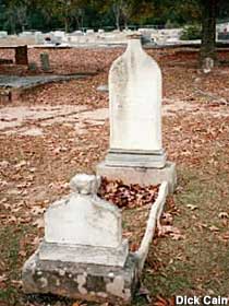 Gravestone is carved in a rough outline shape of a bottle.