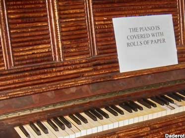 The piano is covered with rolls of paper.
