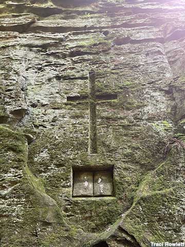 Cross and bible carved into rock wall.