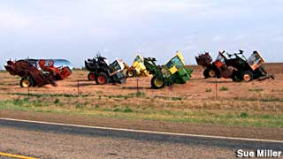 Tractors half-buried, Cadillac Ranch style.    