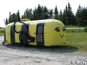 RV painted like a bee is parked along a road.