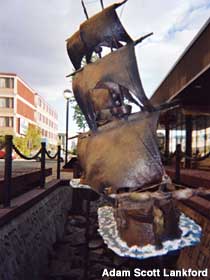 Bronze sculpture of Captain Cook's sailing ship outside a parking garage.