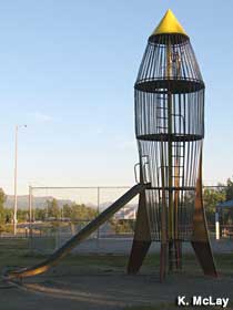 Playground slide emerges from a whimsical space rocket sitting on its tail fins.