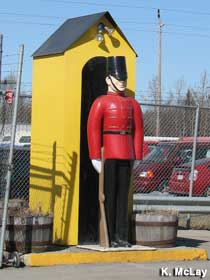 A giant statue of a military guard in an old-fashioned uniform stands in front of a sentry box.