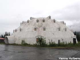Large, white, igloo-shaped building appears to be abandoned.