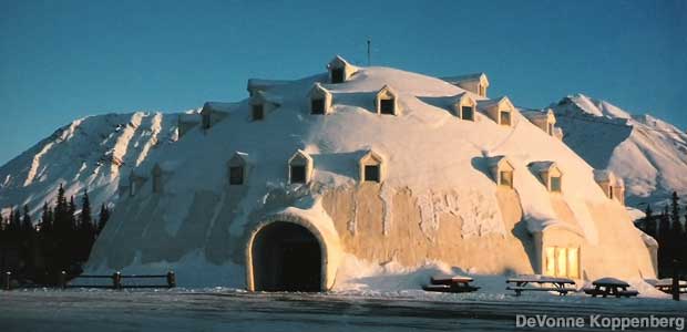Large, white, igloo-shaped building is dusted with snow.