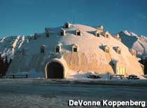 Large, white, igloo-shaped building is dusted with snow.
