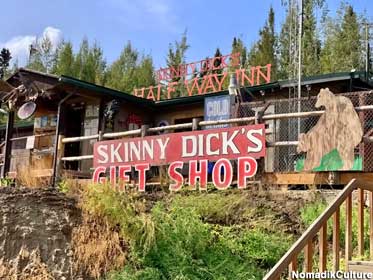 Exterior of Skinny Dick's Halfway Inn has weathered cutouts of bears, large Gift Shop sign.