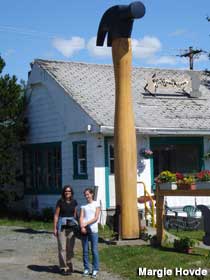 Two people stand next to a 20-foot-high hammer.