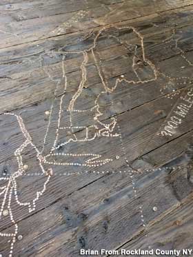Outdoor outline map of the U.S. made from nails hammered into wood.