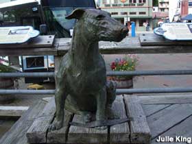 Patsy the Dog's bronze sculpture sits outdoors on a wooden platform.