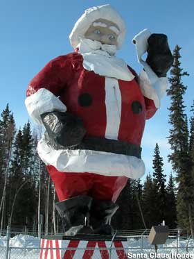Large Santa statue stands in the snow, reading his Naughty or Nice list.