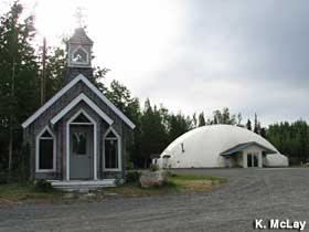 Small, traditional-style church stands next to a domed building.