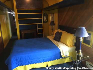 Queen-size bed with pillows and comforter inside a train car.