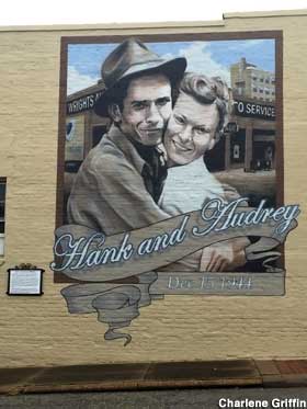 Mural on outside wall of a building of Hank and Audrey Williams hugging cheek to cheek.