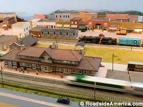 Model train display with moving trains and a miniature old train station.