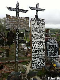 Outdoor folk art of wooden panels and crosses covered with densely painted messages.