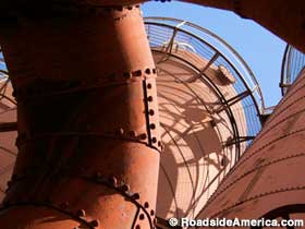 Rust-red pipes and tanks of giant outdoor former ironworks furnaces.
