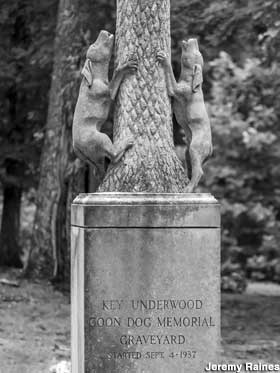 Monument of two dogs looking upward, grasping a tree trunk, at the entrance to the Coon Dog Cemetery.