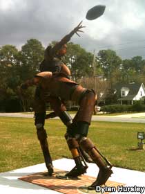 Outdoor sculptures of two football players made of metal junk: one is throwing football, the other is tackling him.