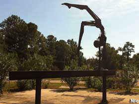 Outdoor sculptures of made of metal junk: a gymnast performing a handstand on a balance beam.