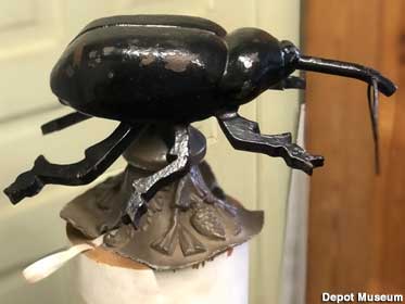 Battered black metal weevil, the size of a small dog, found buried several weeks after its bugnapping.
