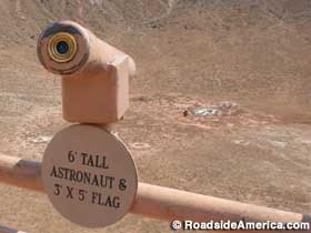 Telescope fixed on 6-ft. tall astronaut and 3-ft. by 5-ft. flag.