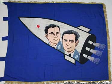 Hero comrades fly skyward on a Socialist Achievement banner.
