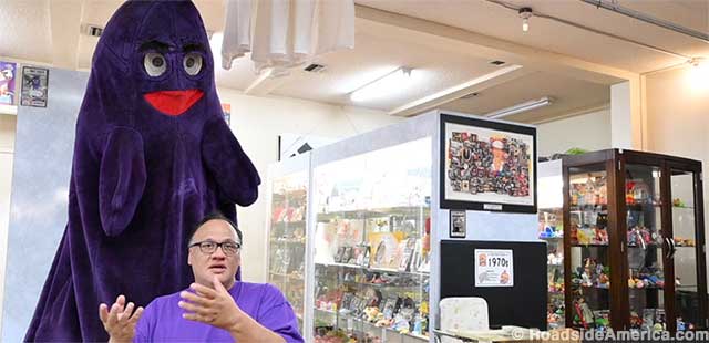 Assistant curator Marvin Hernandez and the museum's towering Grimace.