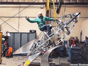 Sculptor Zachary Oxman rides the steel Ray Bradbury rocket sculpture in his studio.