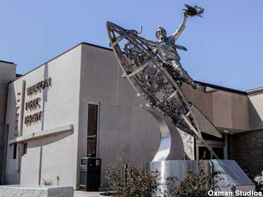 Sculpture of Ray Bradbury astride a steel rocket with library building in the background.