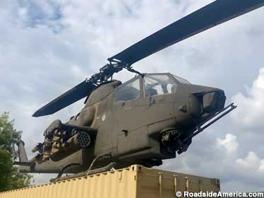 Huey Cobra attack helicopter guards a shipping container.