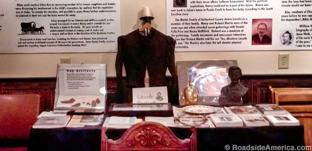 Table display includes a Lincoln bust, a souvenir bottle, a jacket, and lots of reading material.