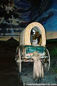 Child pushing a covered wagon.