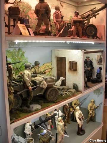Center display: American GIs ready to storm a French farmhouse of Nazis.