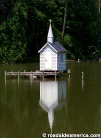 View of tiny church on platform in pond.
