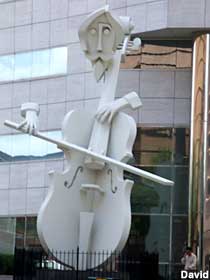 Giant cello with attached cellist head and hands.