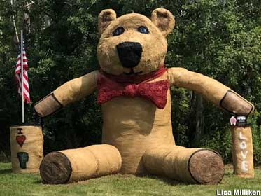 Giant teddy bear -- made of hay bales -- in a bow tie.