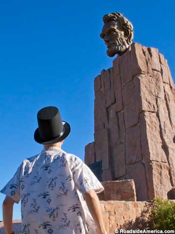 Tourist with stovepipe hat ponders a bare-headed Abe.